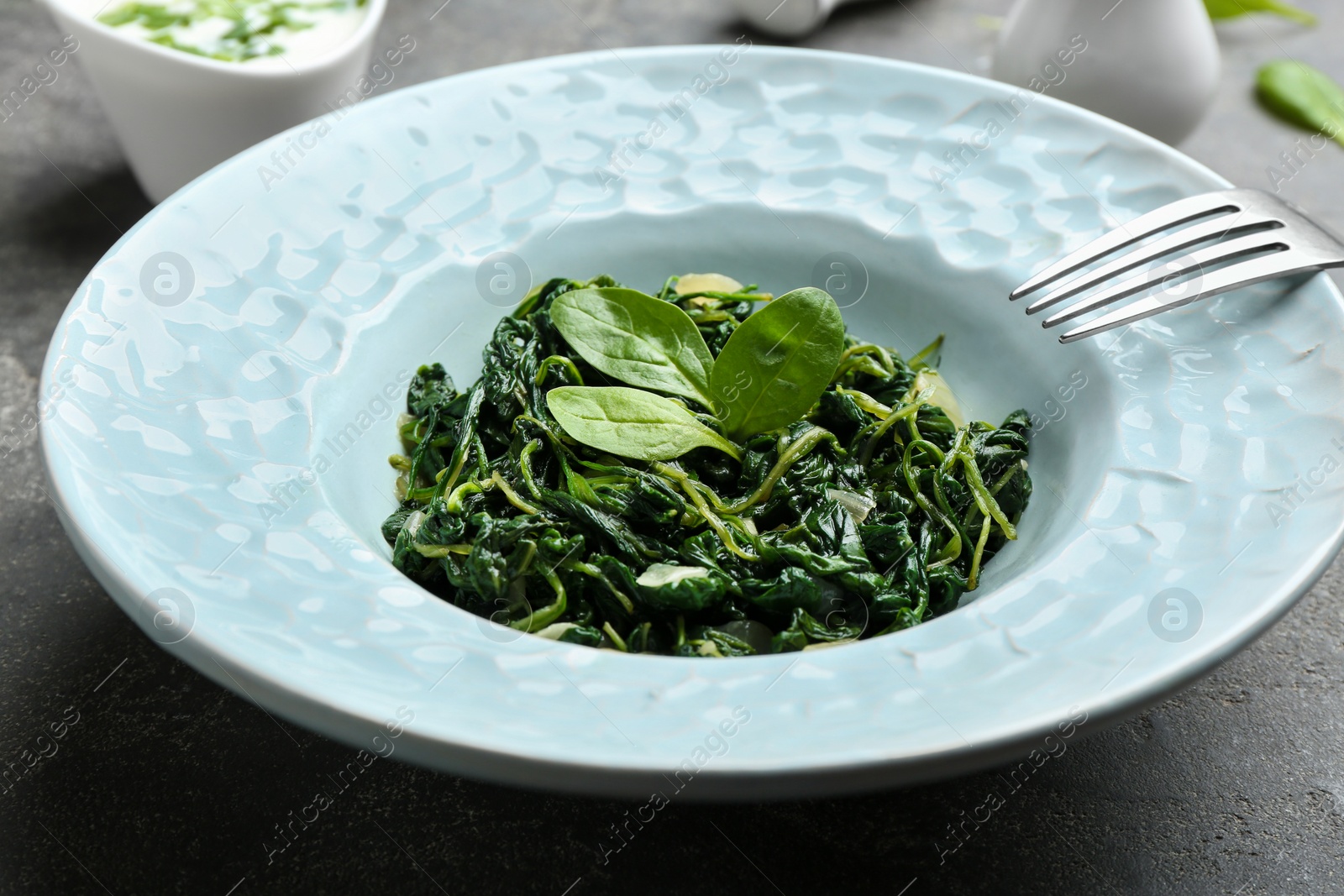 Photo of Plate with tasty spinach on grey  table, closeup. Healthy food