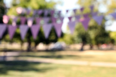Photo of Blurred view of pink bunting flags in park. Party decor
