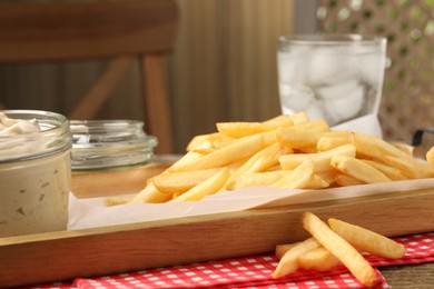 Photo of Delicious french fries served with sauce on wooden table, closeup