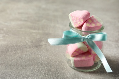 Tasty marshmallows in glass jar on light grey table, closeup. Space for text
