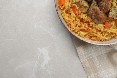 Photo of Delicious pilaf with meat on light grey marble table, top view. Space for text