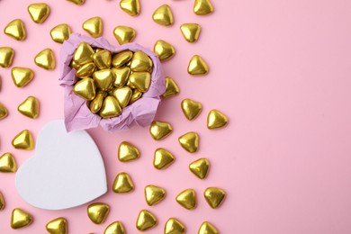 Box and delicious heart shaped candies on pink background, flat lay. Space for text