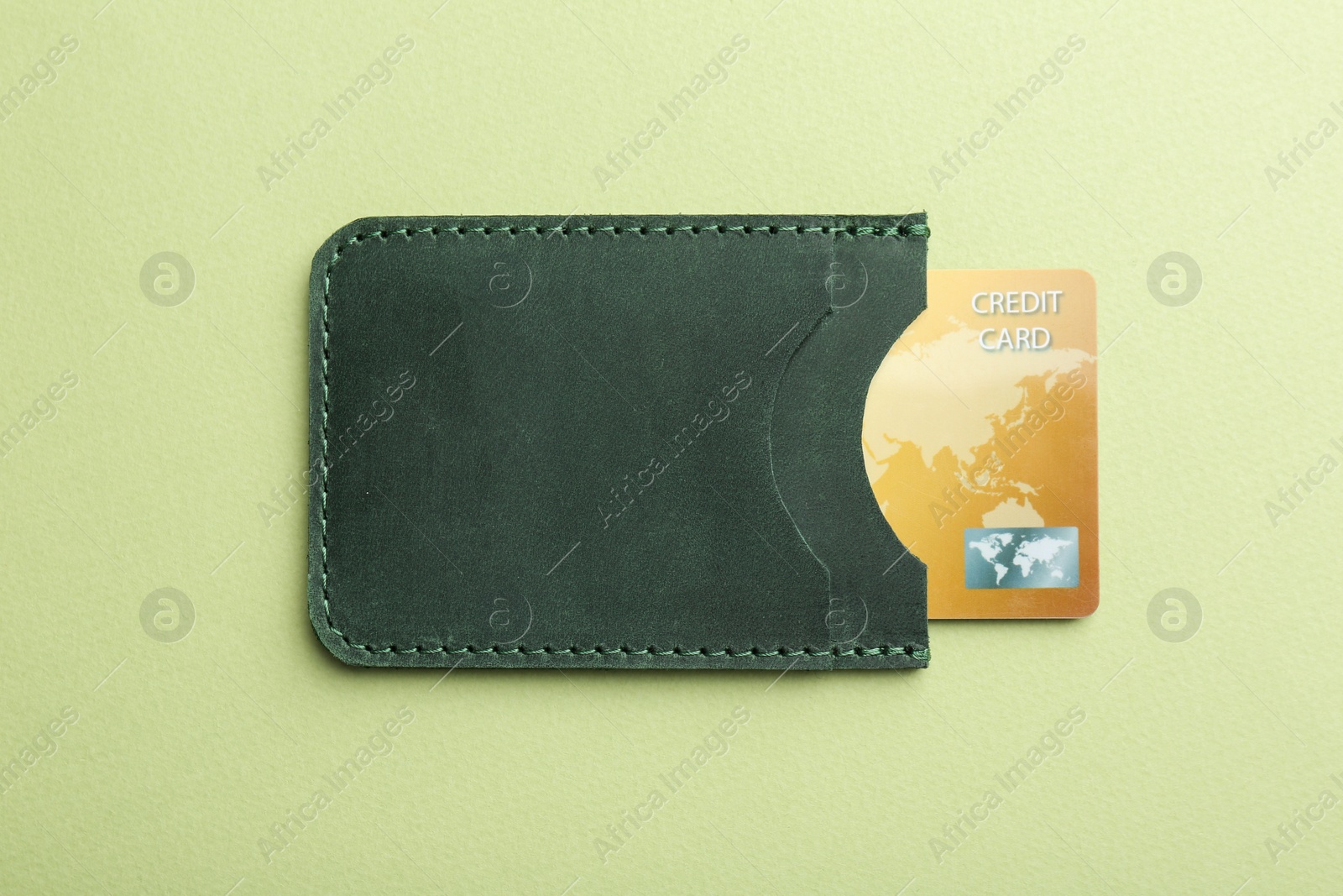 Photo of Leather card holder with credit card on light green background, top view