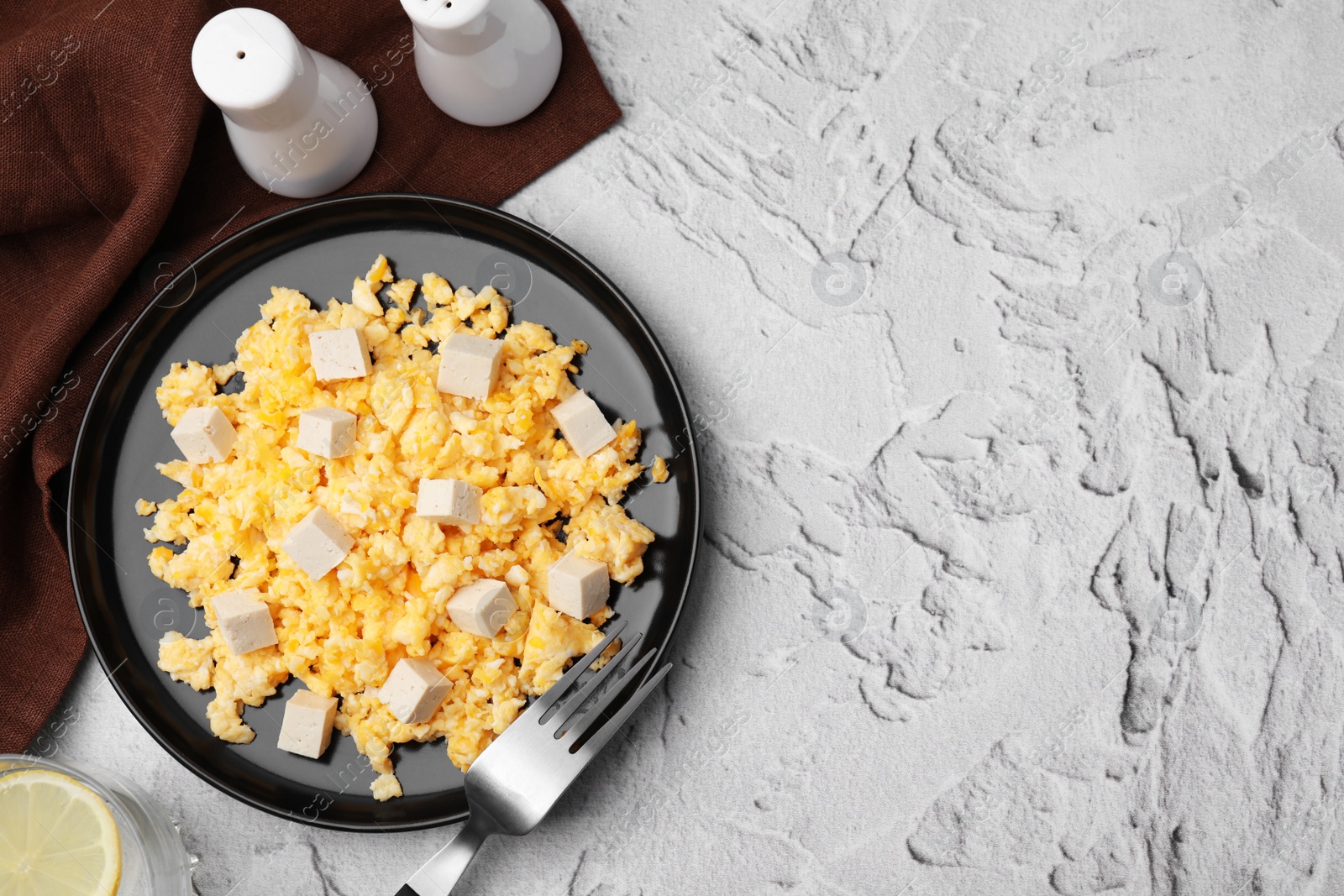 Photo of Plate with delicious scrambled eggs and tofu on white textured table, flat lay. Space for text