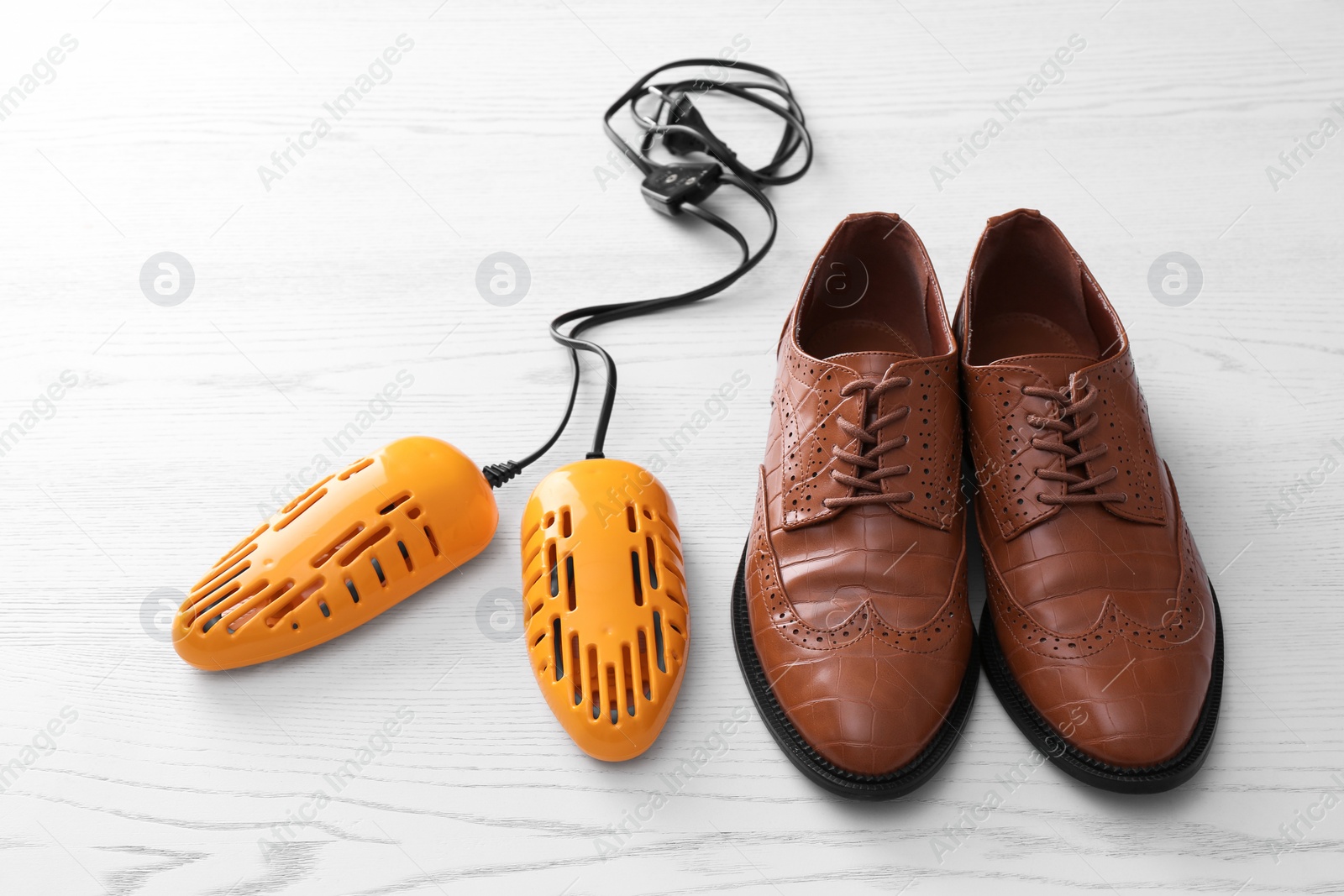 Photo of Shoes and electric dryer on white wooden background