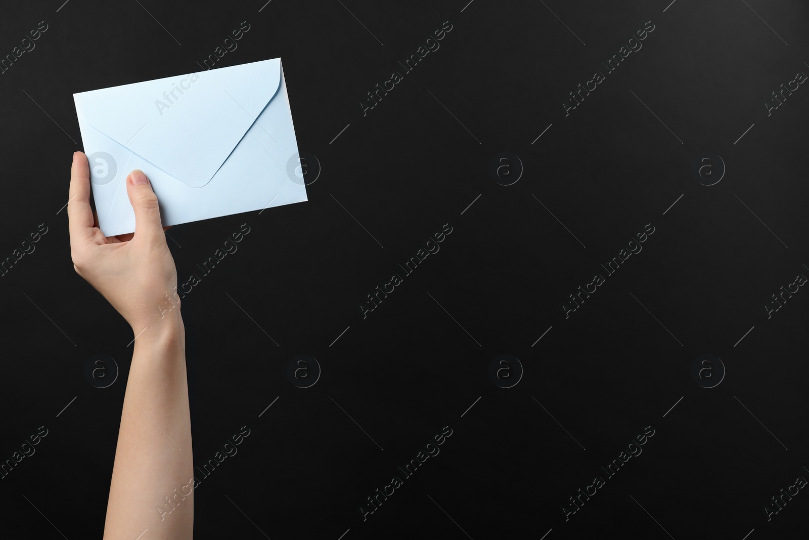 Photo of Woman holding white paper envelope on black background, closeup. Space for text