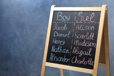 Photo of Chalkboard stand with baby names on blue background