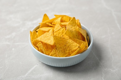 Photo of Tasty mexican nachos chips in bowl on grey table