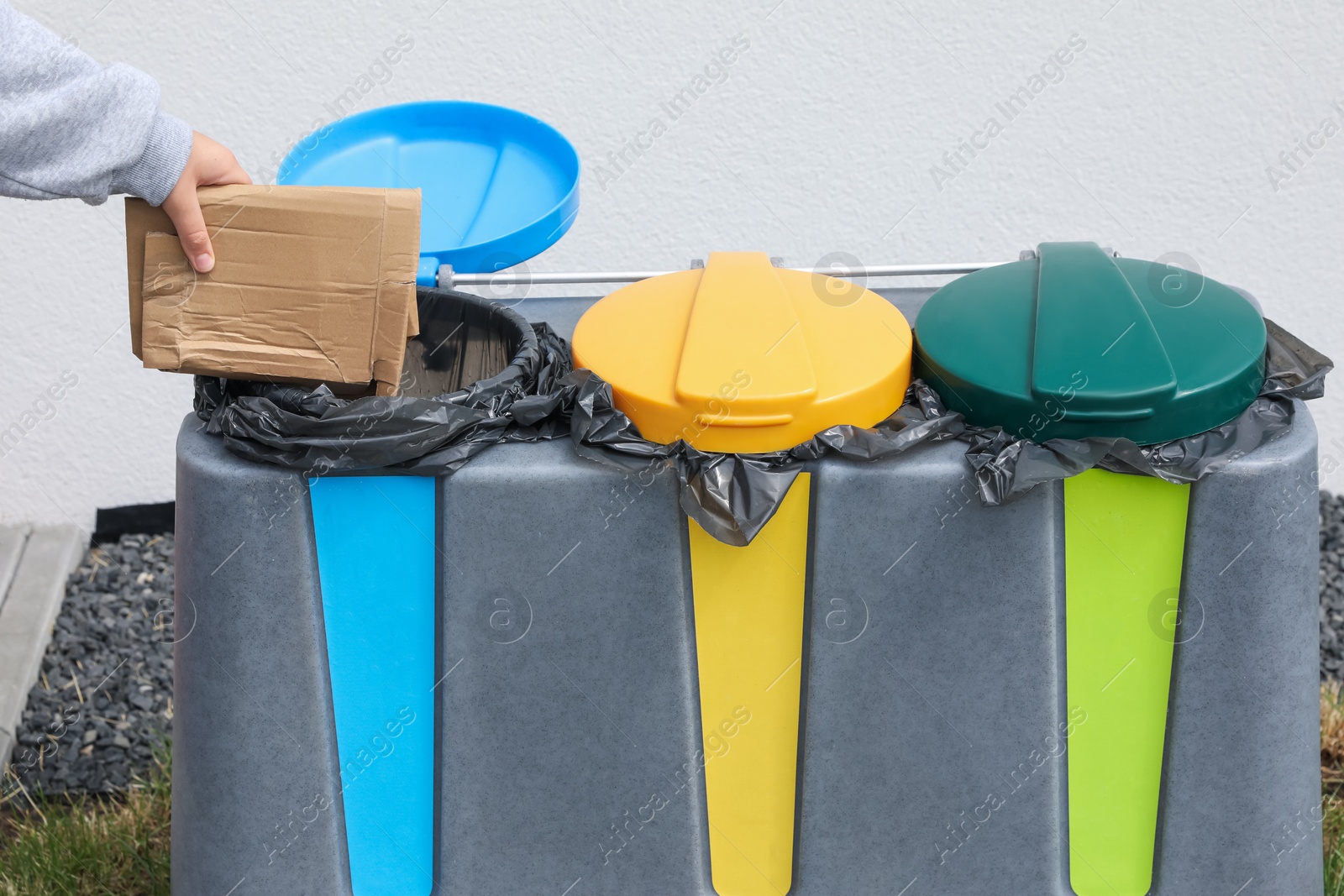 Photo of Woman throwing cardboard in bin outdoors, closeup. Recycling concept