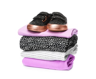 Children's shoes and stack of clothes on white background