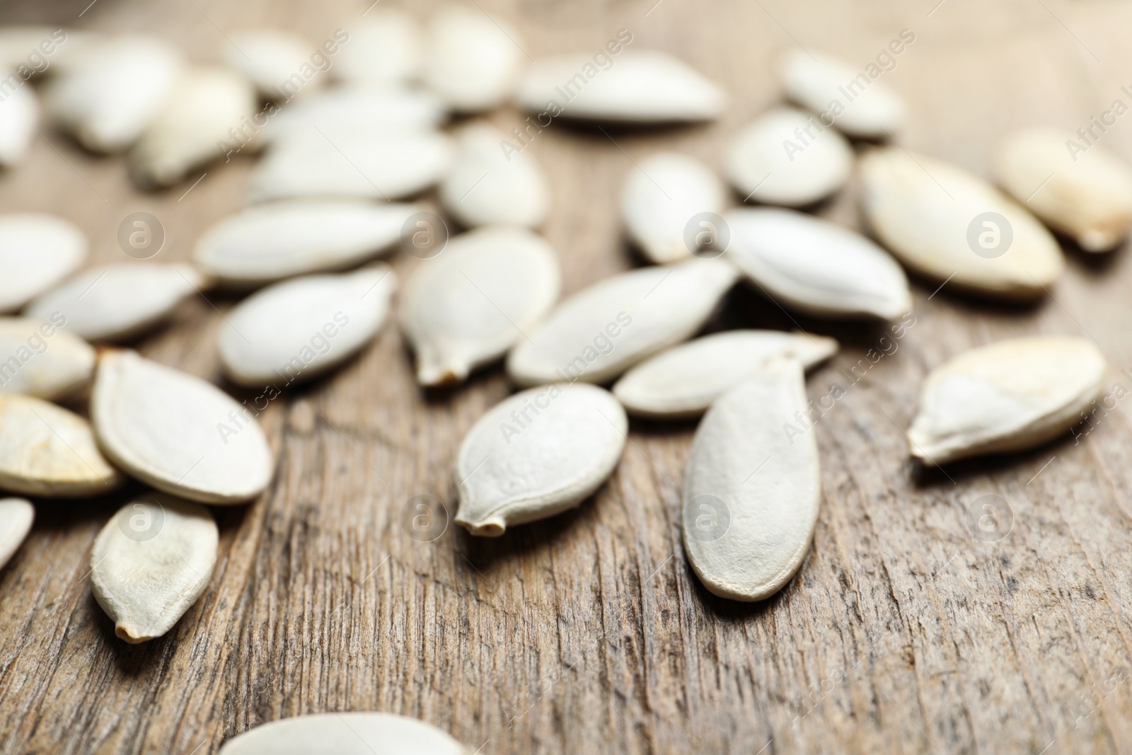 Photo of Raw pumpkin seeds on wooden background, closeup. Vegetable planting