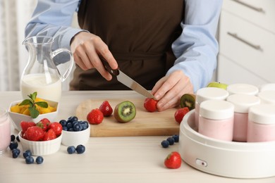 Woman making tasty yogurt at white wooden table indoors, closeup