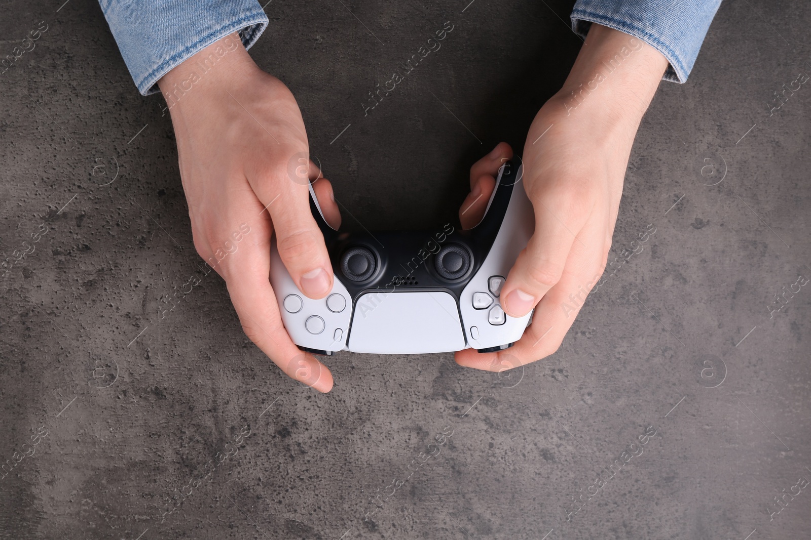 Photo of Man using wireless game controller at grey table, top view