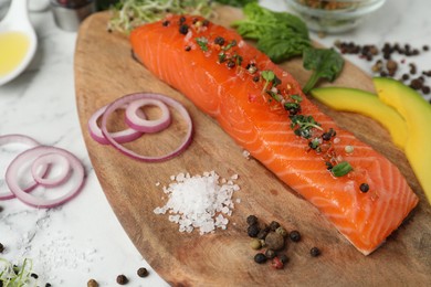 Photo of Delicious salmon with spinach, avocado, spices and onion served on wooden board, closeup