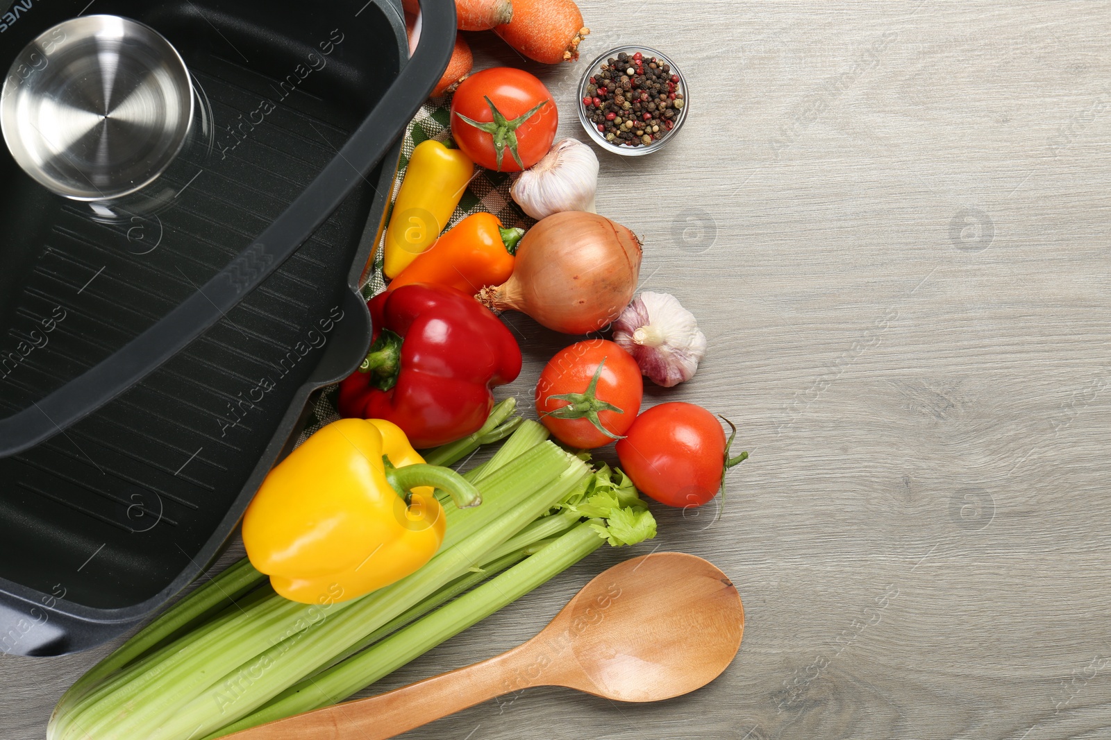 Photo of Black pot, spoon and fresh products on wooden table, top view. Space for text