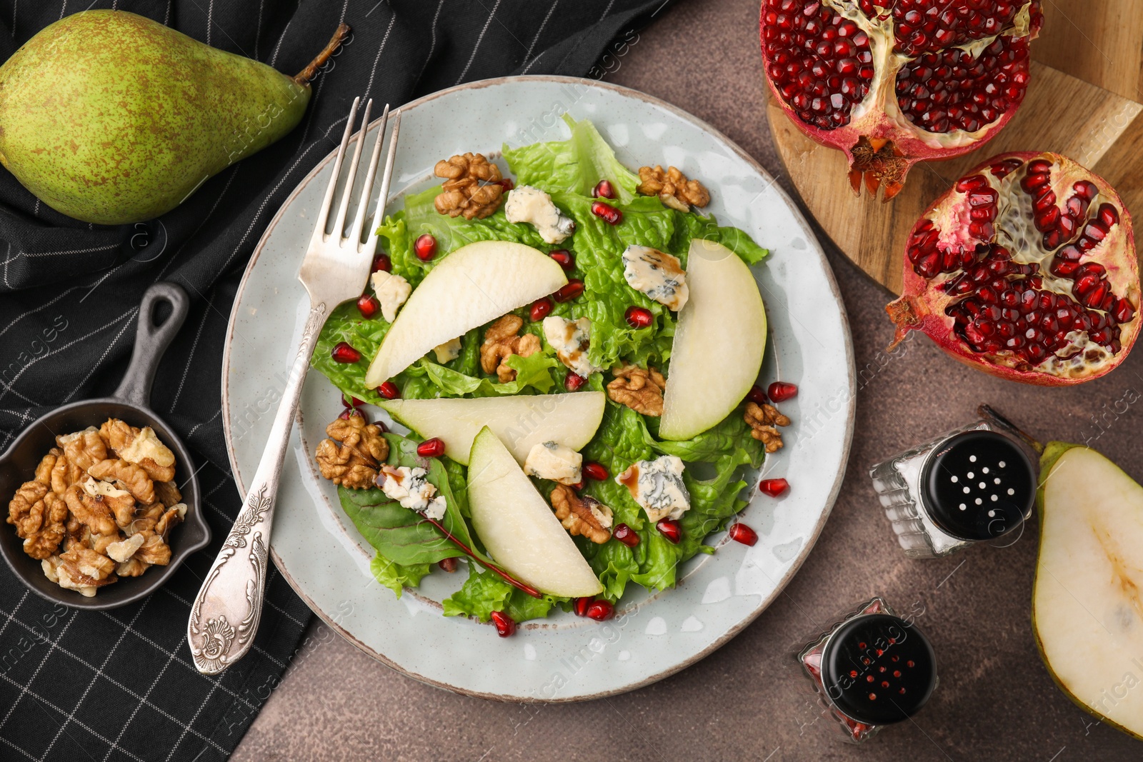 Photo of Delicious pear salad served on dark textured table, flat lay