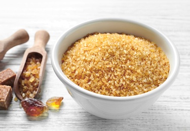 Bowl with brown sugar on wooden background