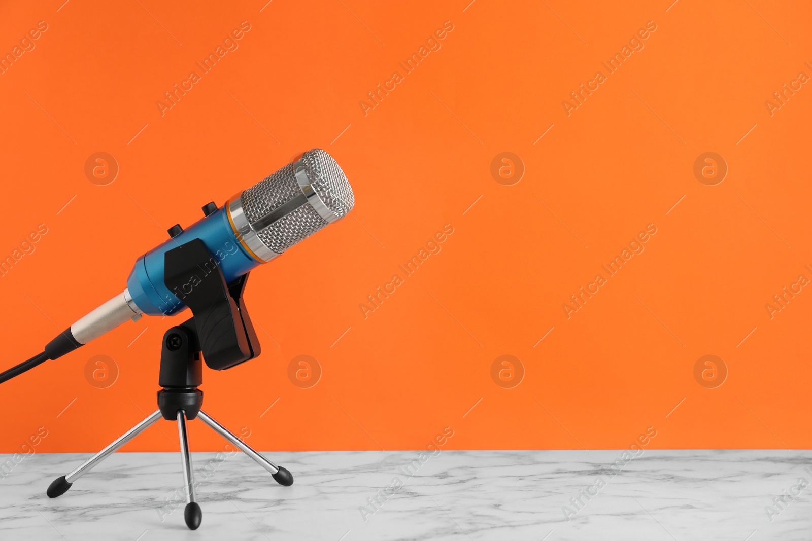 Photo of Microphone on table against color background. Space for text