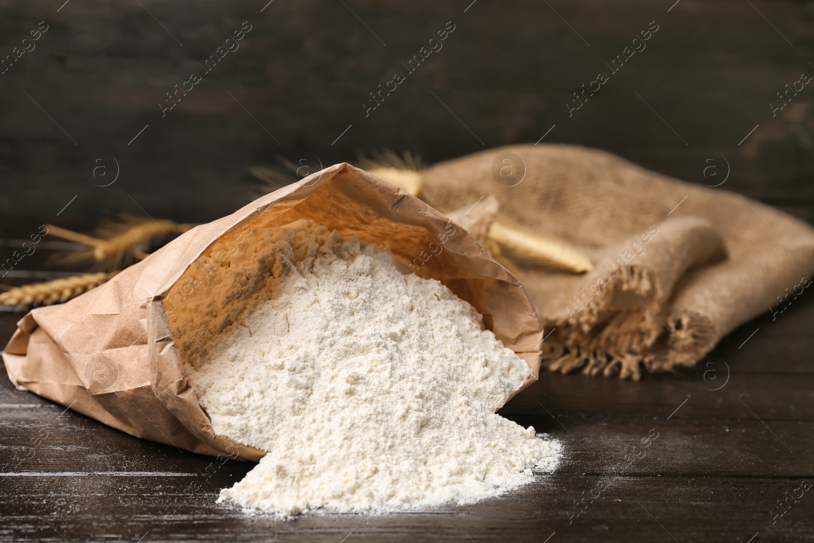 Photo of Paper bag with flour on wooden table