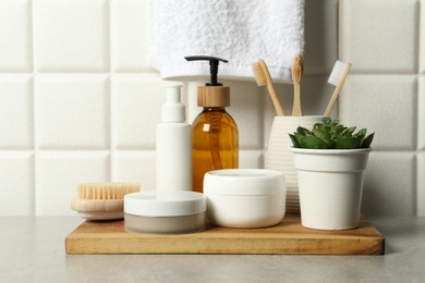 Photo of Different bath accessories and personal care products on gray table near white tiled wall