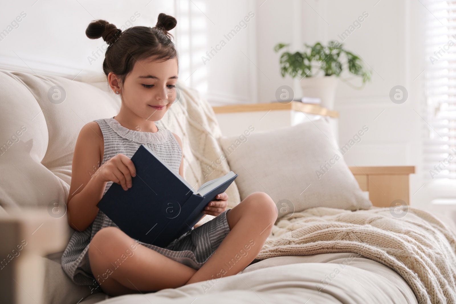 Photo of Little girl reading fairy tale in living room