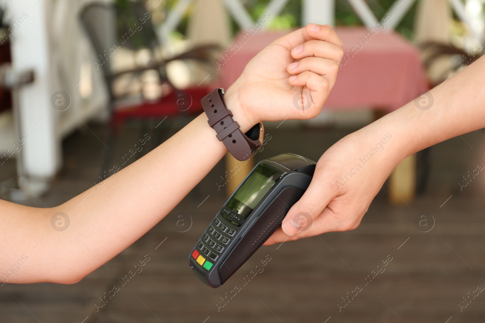 Photo of Woman using smartwatch for contactless payment in cafe, closeup