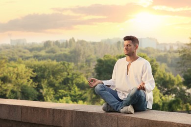 Photo of Man meditating outdoors on summer day. Space for text