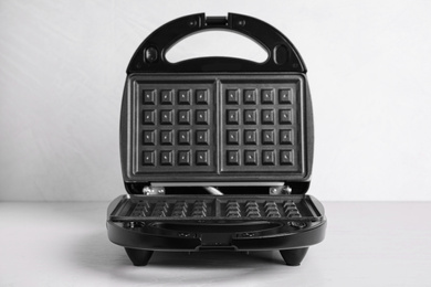 Photo of New modern waffle iron on white table