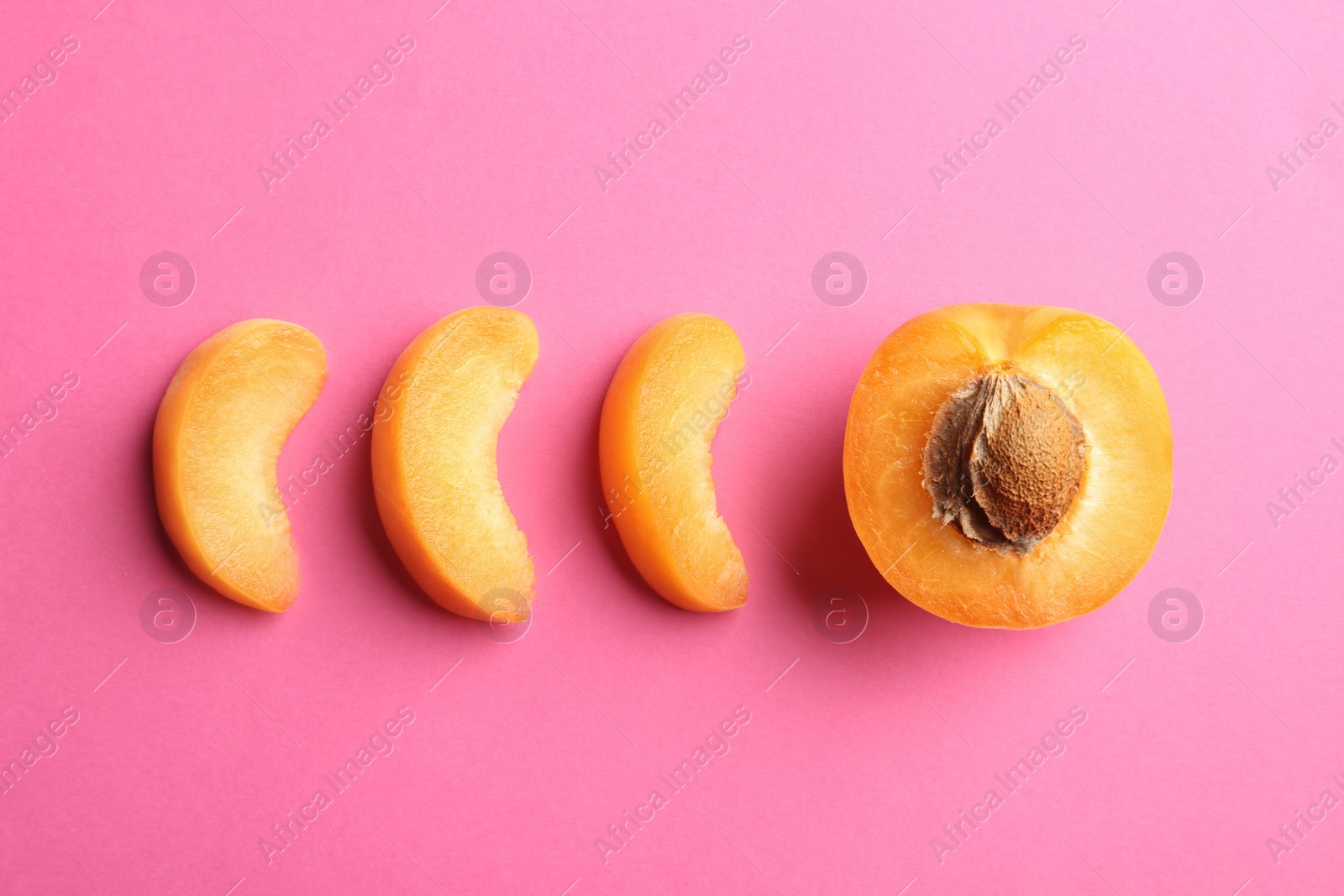 Photo of Pieces of delicious ripe sweet apricot on pink background, flat lay