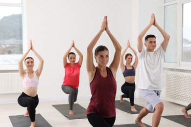 Photo of Group of people practicing yoga on mats indoors