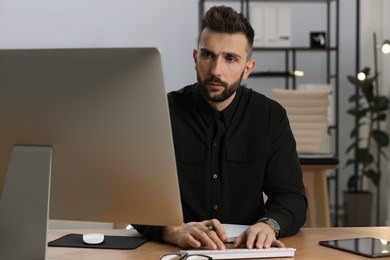 Photo of Man working on computer at table in office