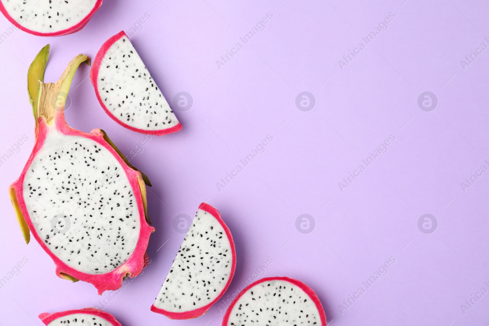 Photo of Delicious cut dragon fruit (pitahaya) on violet background, flat lay. Space for text