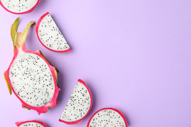 Photo of Delicious cut dragon fruit (pitahaya) on violet background, flat lay. Space for text