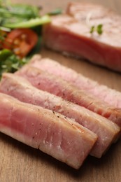 Pieces of delicious tuna steak on wooden board, closeup