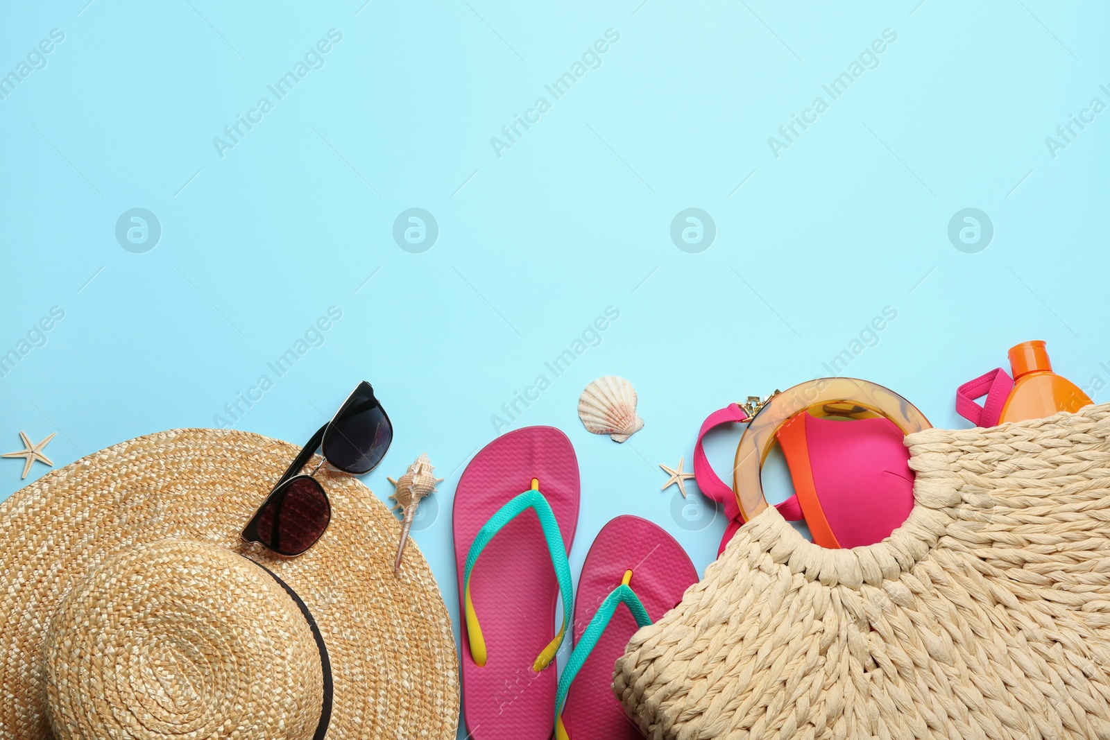 Photo of Beach accessories on light blue background, flat lay. Space for text