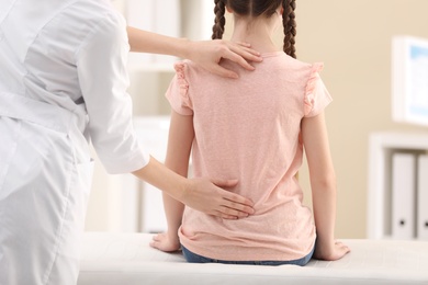 Photo of Chiropractor examining child with back pain in clinic, closeup
