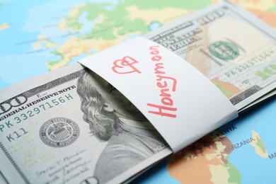 Photo of Stack of money with word Honeymoon on world map, closeup