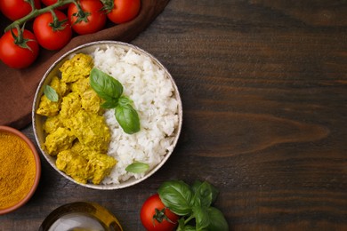 Photo of Delicious rice, chicken with curry sauce and products on wooden table, flat lay. Space for text