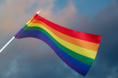 Photo of Bright rainbow LGBT flag against cloudy sky