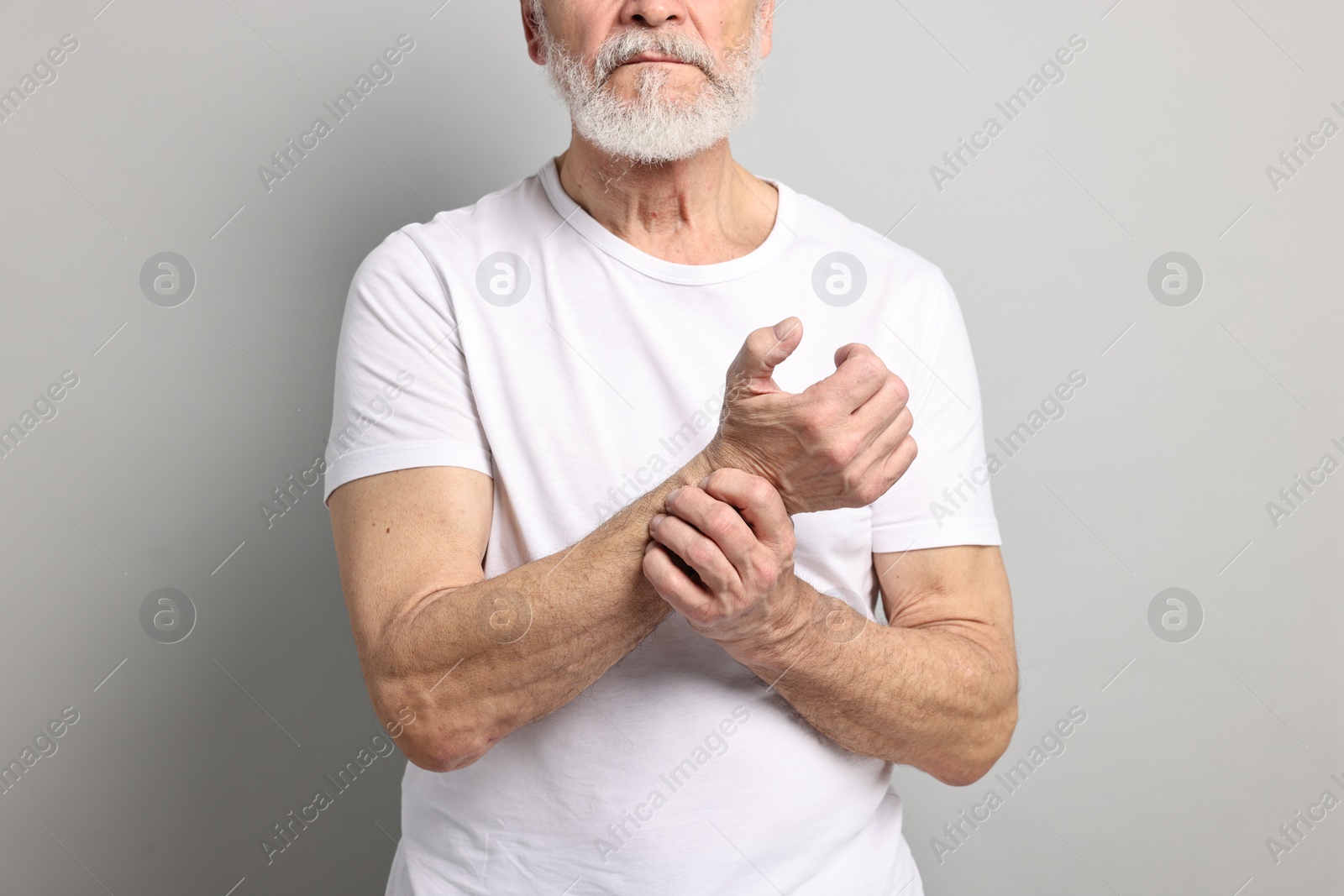 Photo of Arthritis symptoms. Man suffering from pain in wrist on gray background, closeup