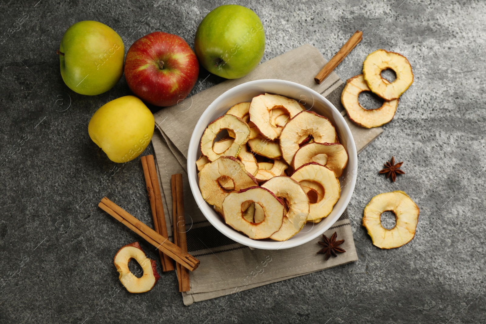 Photo of Delicious apple chips, fresh fruits, anise and cinnamon on grey table, flat lay