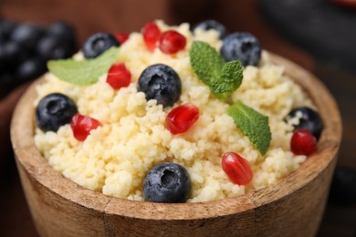 Photo of Bowl of tasty couscous with blueberries, pomegranate and mint, closeup