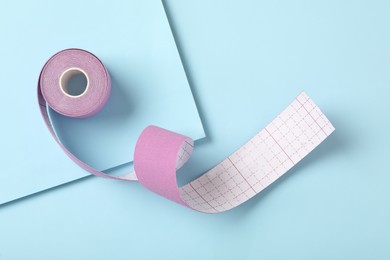 Photo of Bright kinesio tape in roll on light blue background, top view