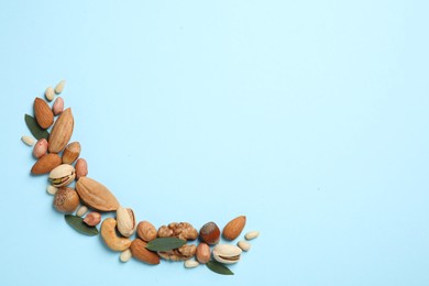 Photo of Different delicious nuts on light blue background, flat lay. Space for text