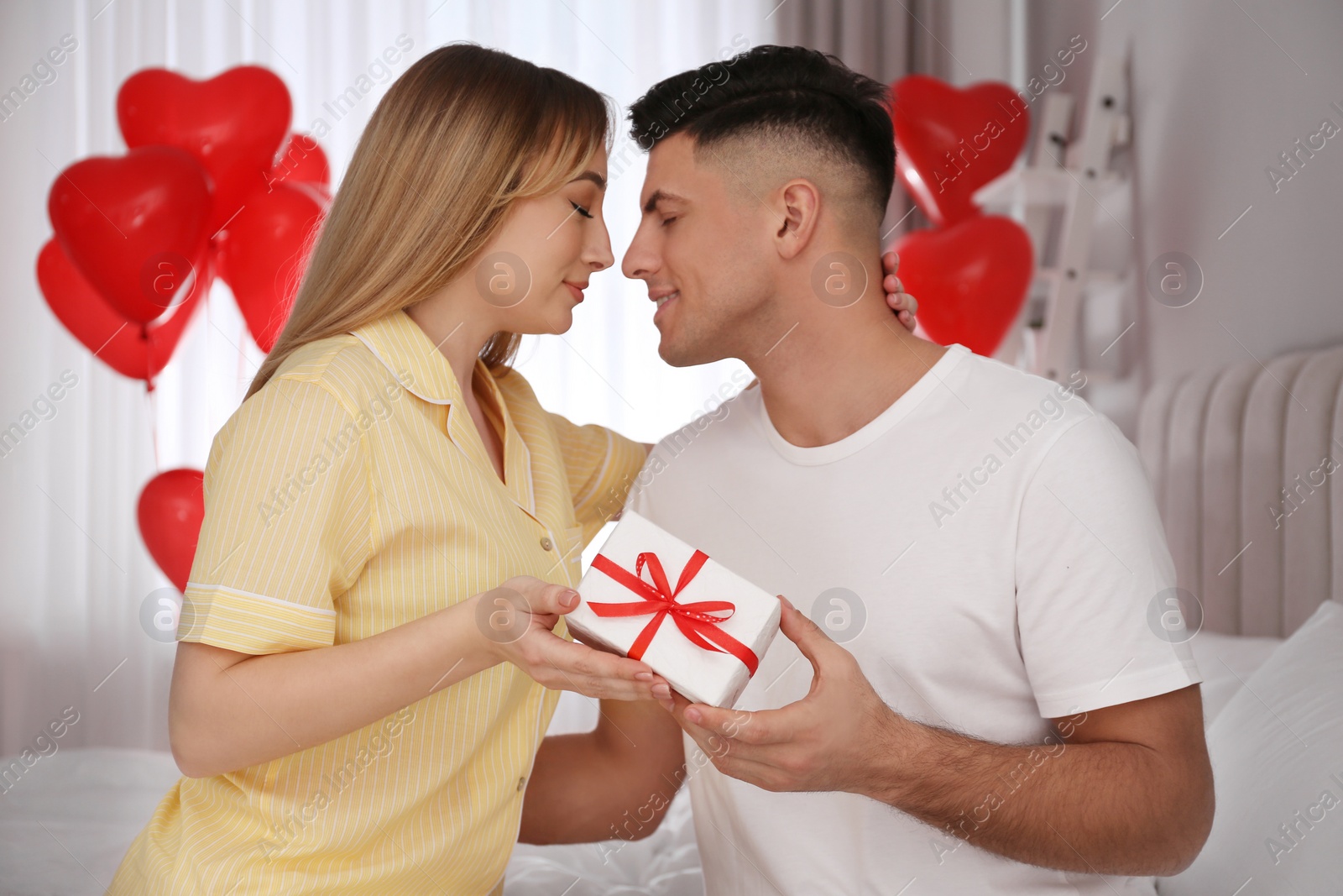 Photo of Lovely couple with gift in room. Valentine's day celebration