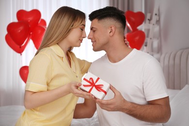 Photo of Lovely couple with gift in room. Valentine's day celebration