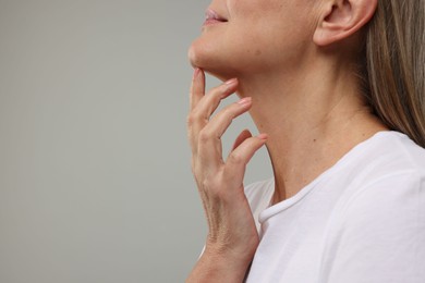 Mature woman with healthy skin on grey background, closeup. Space for text