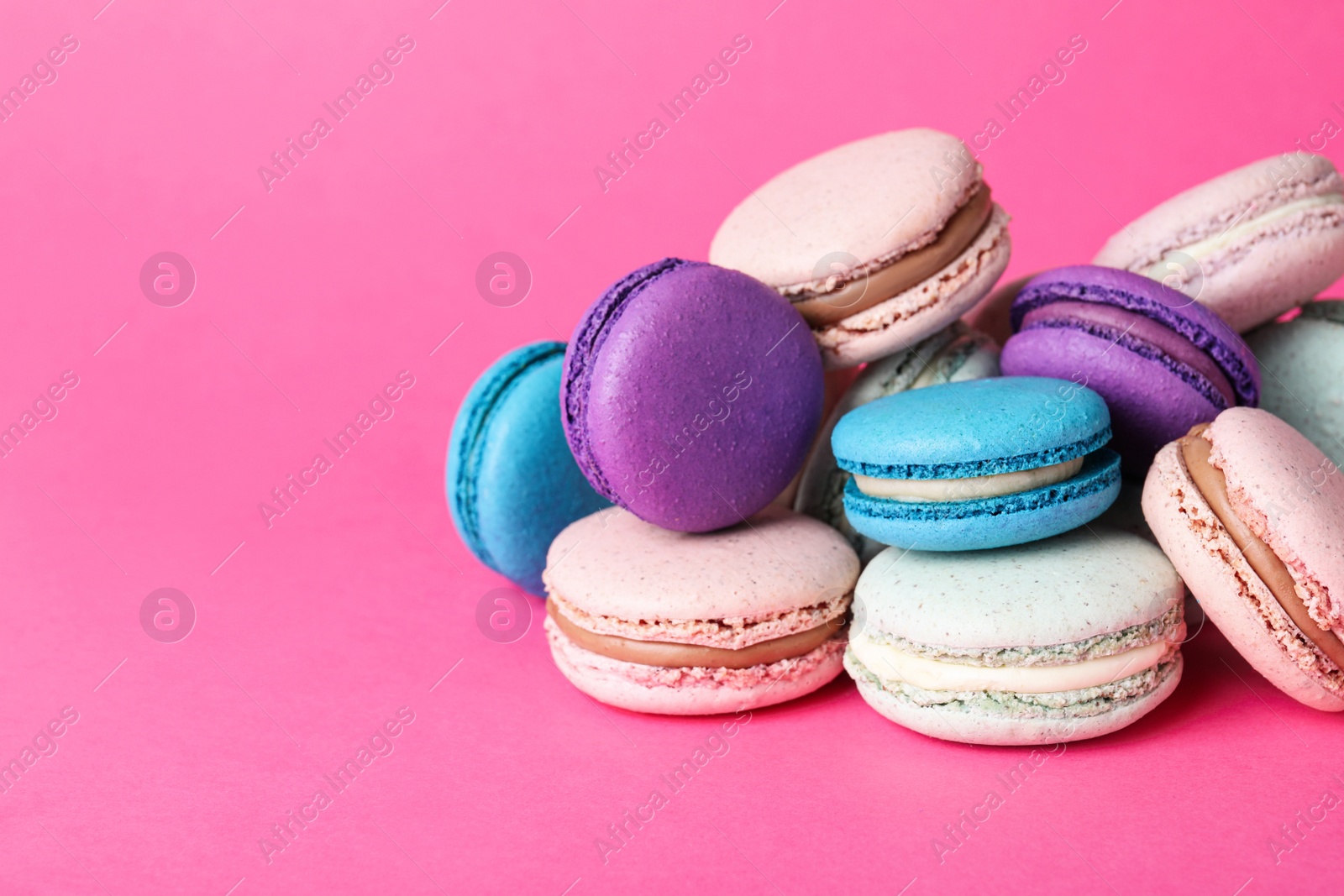 Photo of Pile of delicious colorful macarons on pink background. Space for text
