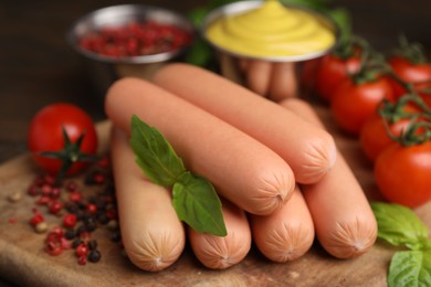 Photo of Delicious boiled sausages, tomatoes, basil and peppercorns on table, closeup