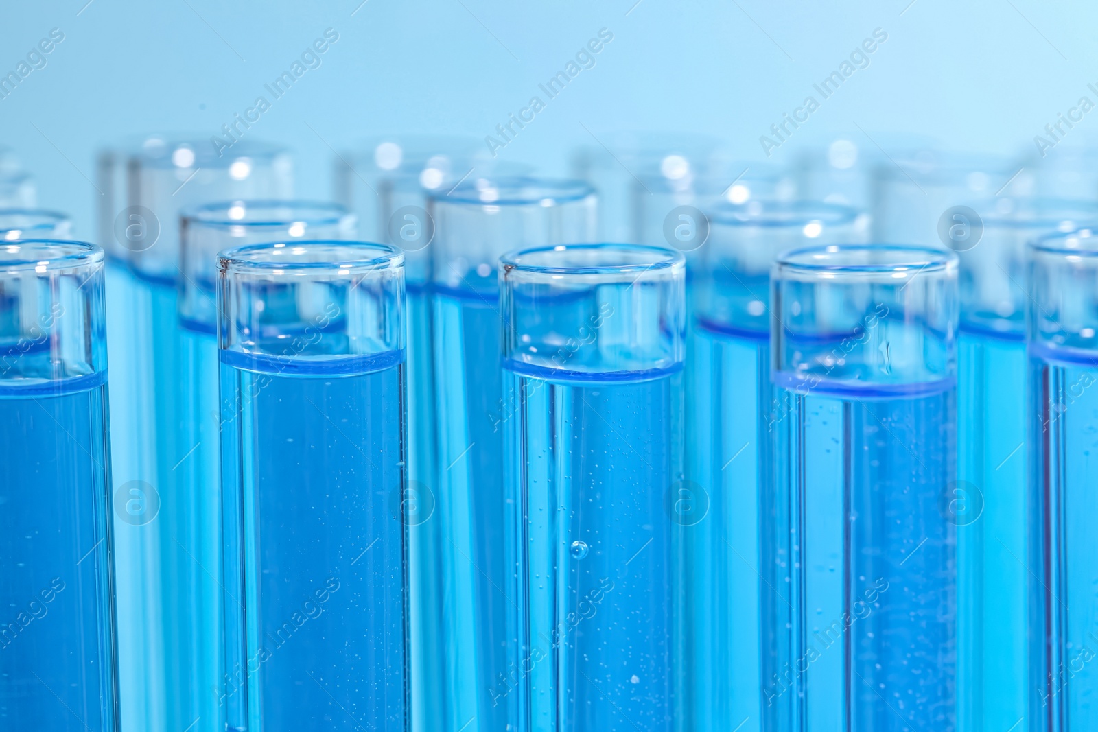 Photo of Test tubes with reagents on light blue background, closeup. Laboratory analysis